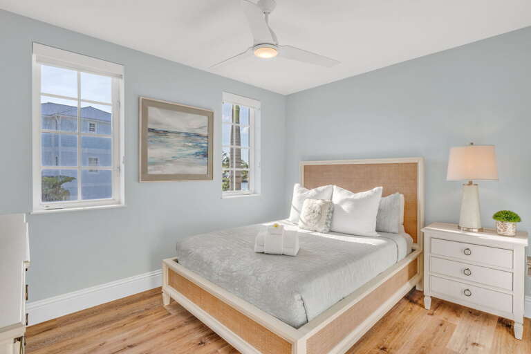 Bright queen bedroom with tropical décor and premium linens—ideal for families booking waterfront homes with pools in the Florida Keys.
