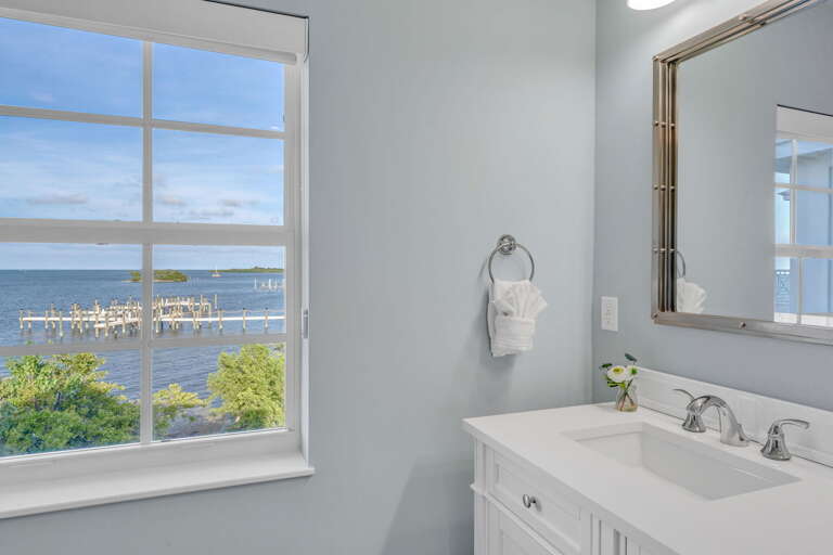 Relax in a calming master bathroom featuring waterfront views, soft lighting, and refined spa-like