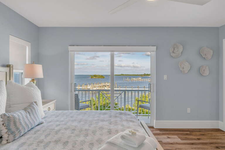 Spacious master suite with king bed, private balcony access, and serene gulf coast views—perfect for guests seeking upscale Florida Keys vacation rentals with a heated pool and lounge area.