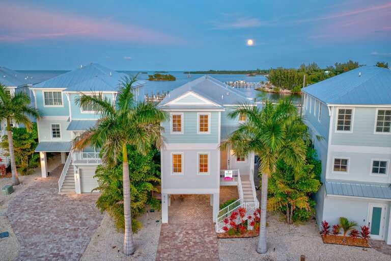 Stunning night view of a luxury water-front home under the moonlight, highlighting the private pool, outdoor seating, and tropical landscaping—perfect for a romantic or serene Florida Keys getaway.