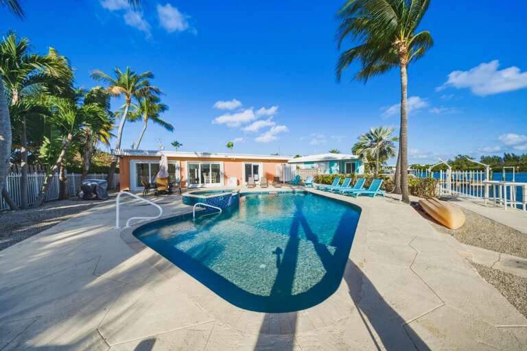 Beautiful backyard retreat with private pool, hot tub, loungers, and gas grill for cooking fresh catch after fishing.