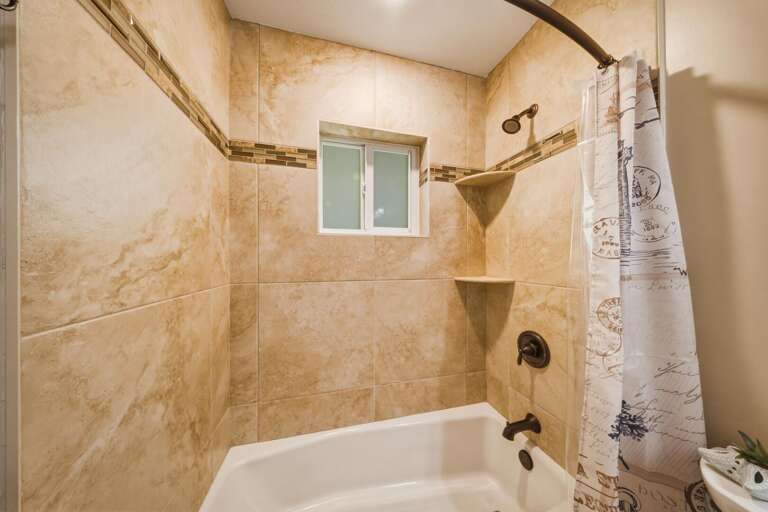 This full bathroom includes a tub/shower combo and large vanity, providing convenience for multiple