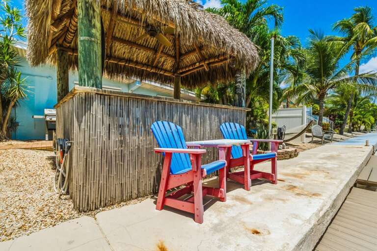 This private tiki hut features bar seating and canal views, creating a great outdoor gathering space for boating, fishing, and relaxing in the Florida Keys.
