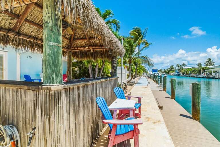 The tiki hut creates a comfortable outdoor living area with shade, seating, and direct views of the canal at this pet-friendly Key Colony Beach vacation rental.