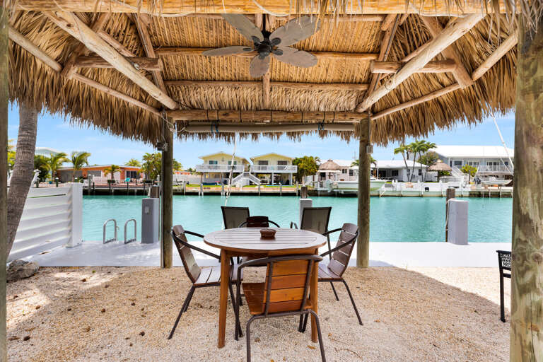 Relax under the tiki hut with table seating, palm-lined turf, and canal views at this pet-friendly Key Colony Beach Florida Keys getaway.