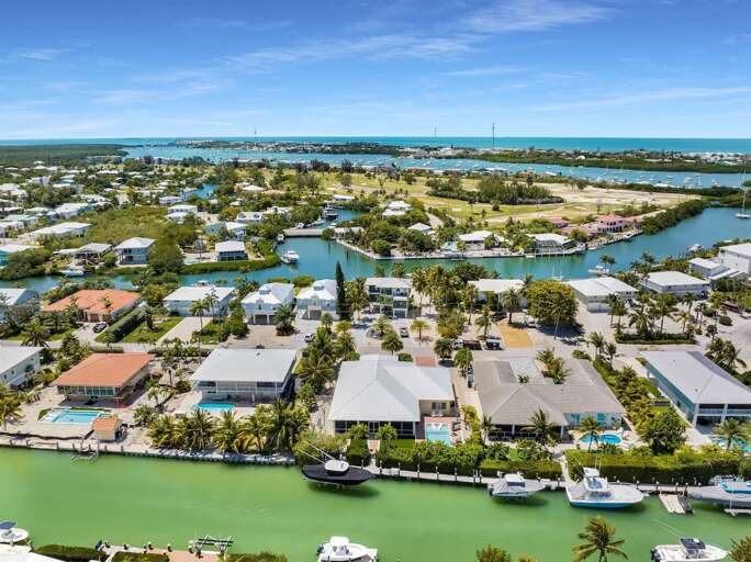 This aerial perspective showcases neighborhood canals, boats, tropical homes, and the surrounding Florida Keys landscape.