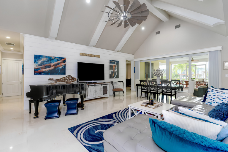.This bright living room features vaulted ceilings, comfortable seating, coastal artwork, a piano, and access to the screened patio.