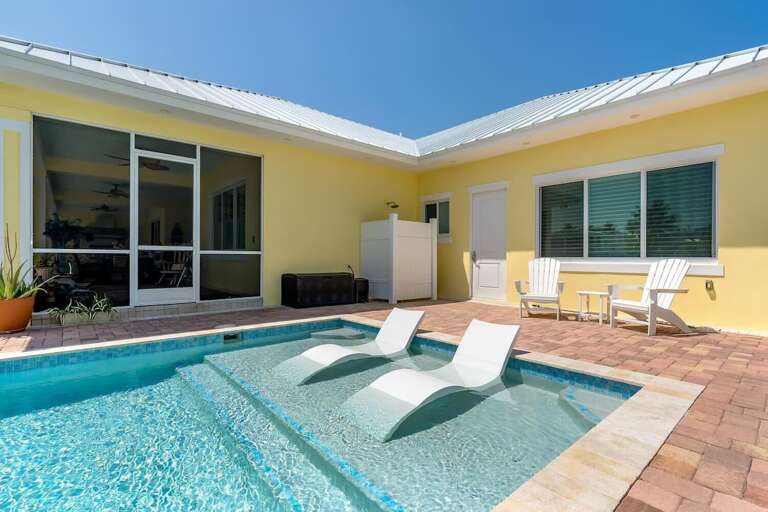 Casa Del Sol's sparkling pool features a shallow sun shelf with in-water lounge chairs and a spacious brick patio.