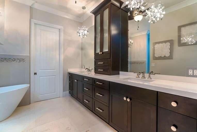 An expansive double vanity, generous storage, decorative mirrors, and elegant lighting complete this bright primary bathroom.