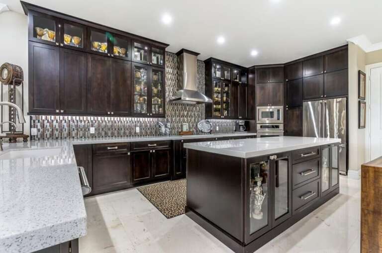 This spacious kitchen features dark wood cabinetry, granite countertops, stainless-steel appliances, and a large center island.