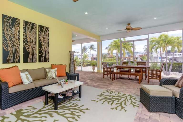 A spacious screened lanai offers cushioned seating, ceiling fans, outdoor dining, and views of the private pool.
