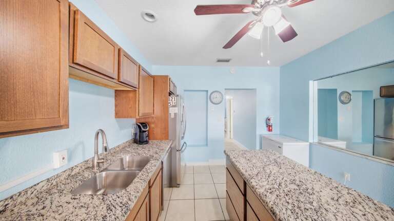 This spacious kitchen features a double sink, granite counters, wood cabinets, stainless-steel appliances, and bar seating.