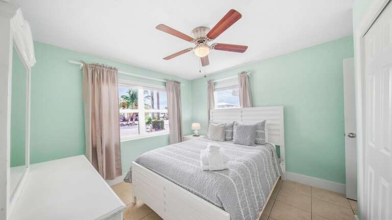 Two sunny windows, neutral coastal decor, and a comfortable bed give this bedroom an airy Florida Keys atmosphere.
