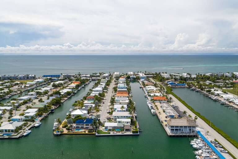 A sweeping aerial photograph showcases the surrounding boating canals and the property's proximity to the Atlantic Ocean.