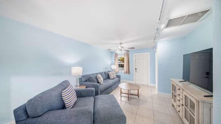 This welcoming living area features sectional seating, a large television, tiled floors, and an open layout for relaxing together.