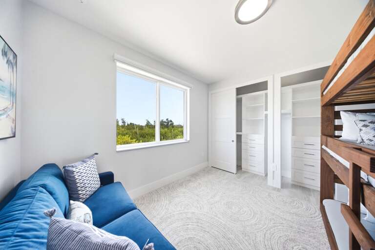 This family-friendly bedroom offers bunk beds, a comfortable sofa, closet storage, and a sunny window overlooking the tropical surroundings.