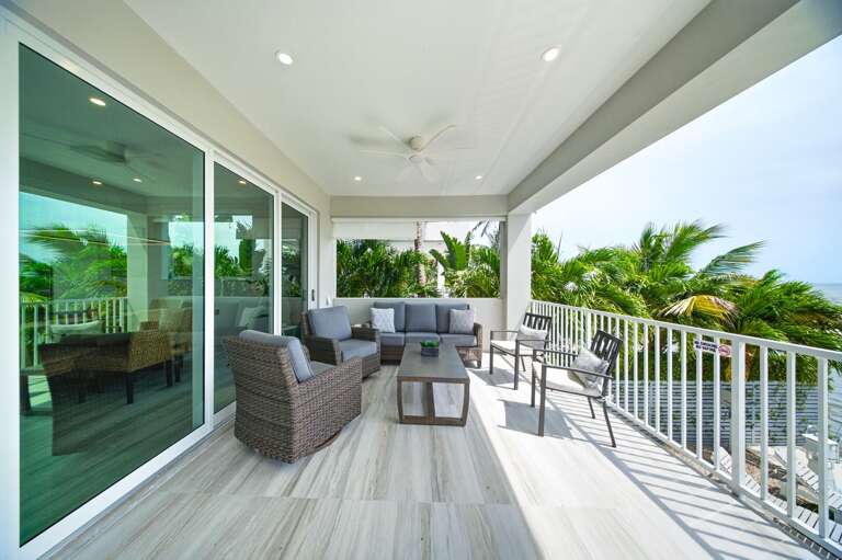 Relax on the covered balcony with comfortable seating, tropical breezes, and sweeping views of the surrounding canal.