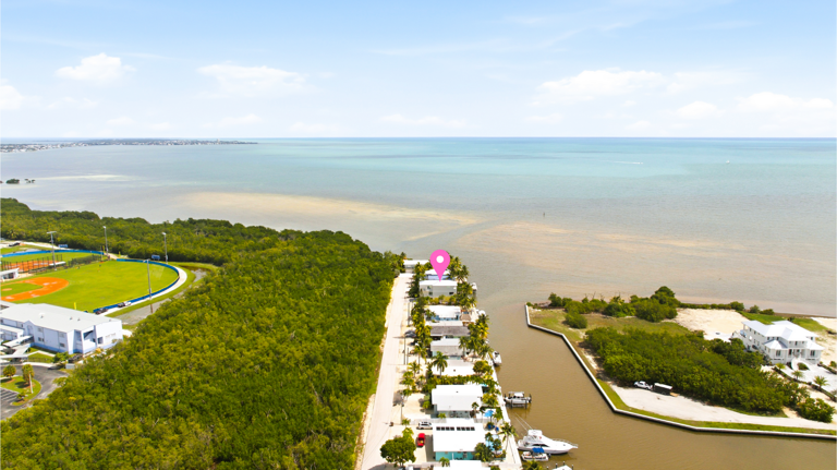 This aerial view highlights the home's coastal location, tropical surroundings, and proximity to open water.