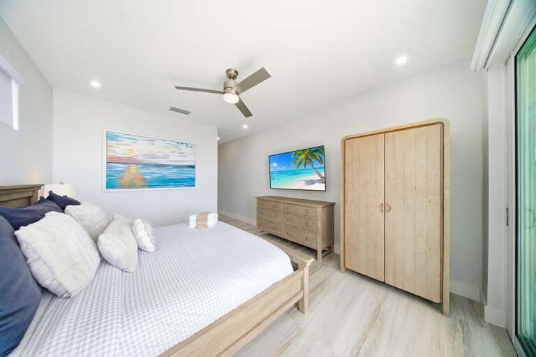 Soft coastal colors, natural wood furniture, a ceiling fan, and a large television create a peaceful Florida Keys retreat.