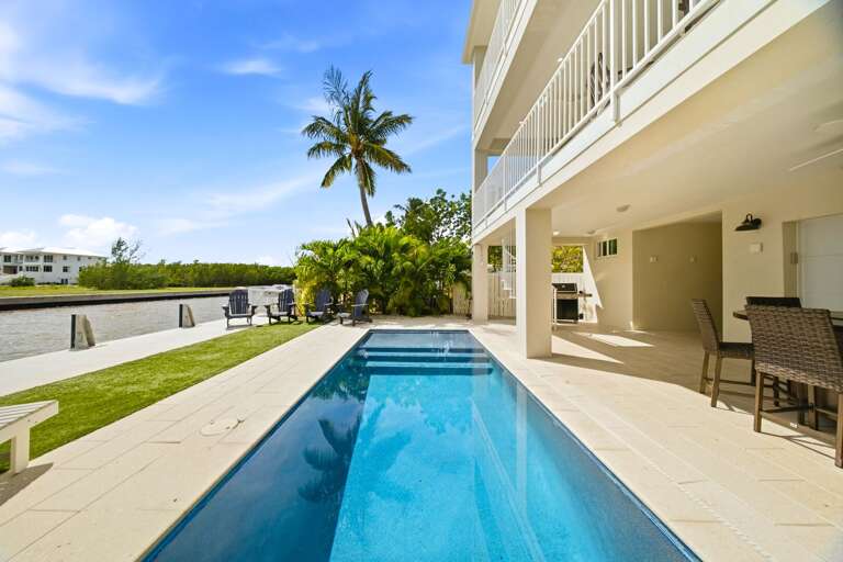 Cool off in a sparkling private pool surrounded by a spacious patio and shaded outdoor areas beside the water.