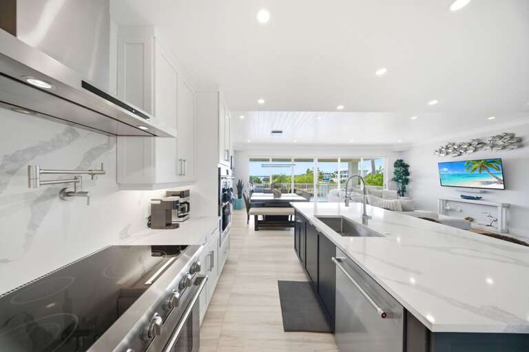This spacious kitchen features white cabinetry, generous countertops, modern appliances, and a large island for preparing vacation meals.