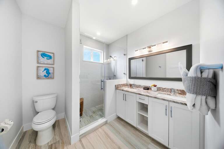 This private bathroom features a long vanity, generous storage, a large mirror, and a glass-enclosed walk-in shower.