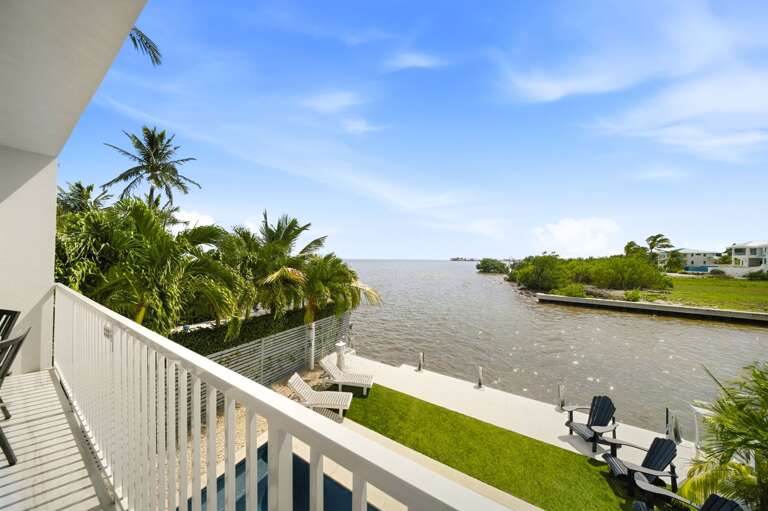 The elevated balcony overlooks calm canal waters, tropical landscaping, and the beautiful coastal scenery of Marathon.