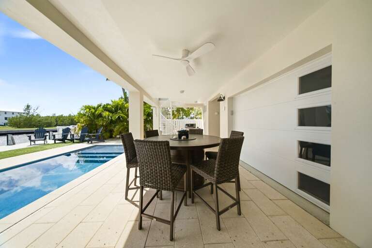 Enjoy outdoor meals in a shaded dining space overlooking the private pool and tropical waterfront surroundings.