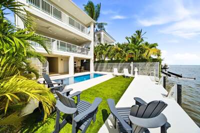 Adirondack chairs, tropical landscaping, a private pool, and direct dock access create an ideal Florida Keys outdoor retreat.