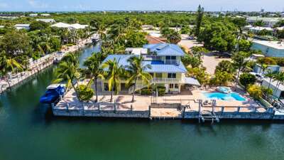 This aerial perspective highlights the canal front dock, private pool, expansive patio, and tropical outdoor spaces.