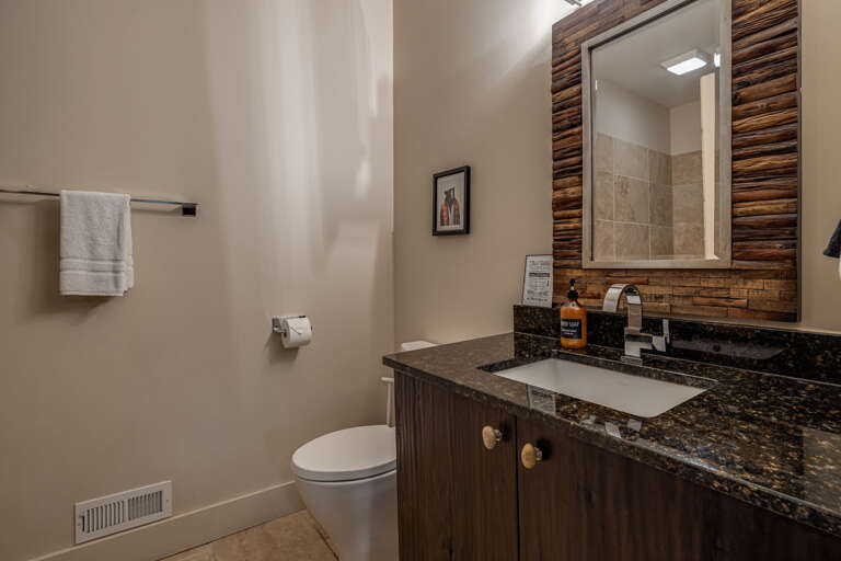 Step into your private bathroom featuring rich wood accents and elegant granite countertops. Crisp white towels await while warm lighting creates a welcoming atmosphere perfect for unwinding after a mountain adventure.