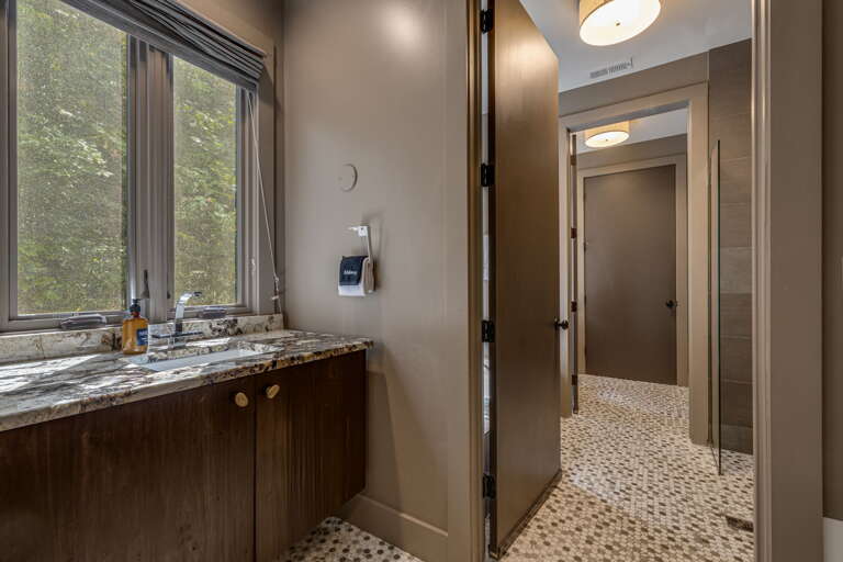 Step into your private sanctuary with a spa-like bathroom featuring elegant granite countertops, forest views through tranquil windows, and a thoughtfully designed layout that invites relaxation.