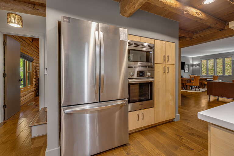 Your dream kitchen awaits with gleaming stainless steel appliances, warm wood cabinetry, and rustic exposed beams overhead—perfect for preparing meals in style.