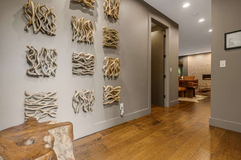 Step into a warm, coastal-inspired entry where driftwood art anchors your arrival and rich hardwood floors lead you deeper into your retreat.