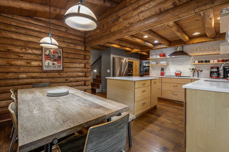 Your private mountain retreat features a fully equipped chef's kitchen with modern appliances, rustic log walls, and a handcrafted dining table—perfect for gathering with loved ones.
