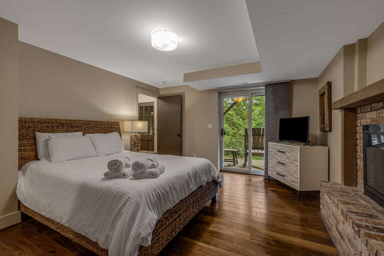 Unwind in your serene bedroom with a plush bed, warm hardwood floors, and a private balcony overlooking lush greenery—your peaceful retreat awaits.