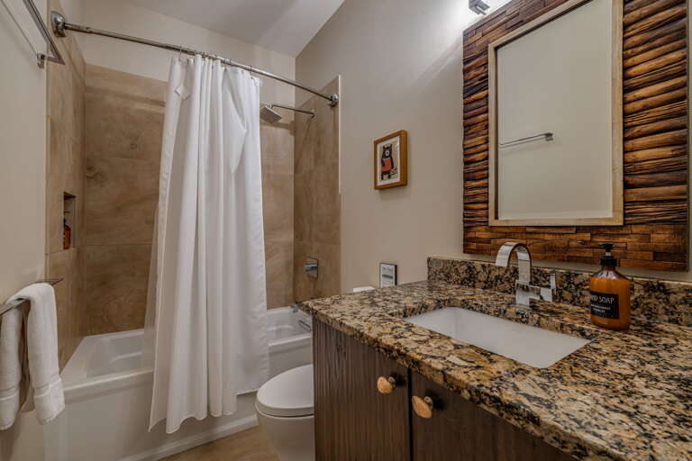 Refresh in your private bathroom featuring a spacious tub-shower combo, granite countertops, and warm wood accents that blend modern comfort with rustic mountain charm.