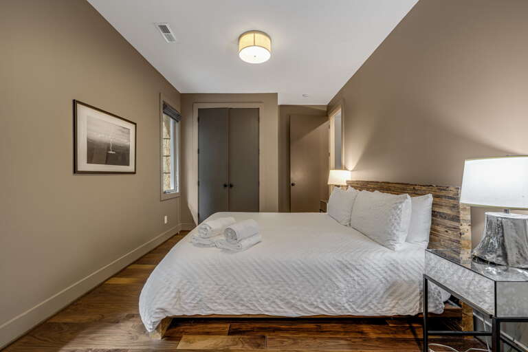 Slip into crisp white linens beneath a rustic reclaimed wood headboard. Warm earth tones wrap you in calm, while soft lighting and thoughtful touches make your retreat feel effortlessly serene.