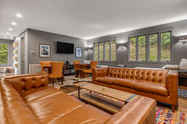 Sink into rich leather sofas surrounded by forest views through expansive windows. This stylish space blends modern comfort with natural beauty for your perfect retreat.