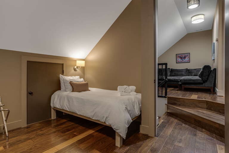 Step into your cozy retreat with vaulted ceilings and warm wood floors. A plush bed awaits you in one room, while a comfortable lounge space invites you to unwind just steps away.