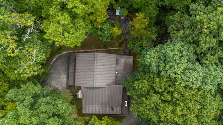 Aerial view of the vacation property nestled in a lush, tree-filled natural landscape, offering a tranquil forest setting for a secluded retreat.