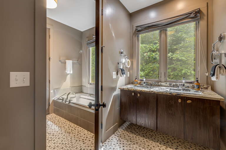 Unwind in your spacious bathroom, where natural light pours in through large windows overlooking lush greenery. The deep soaking tub and elegant granite vanity create a serene retreat after your day.