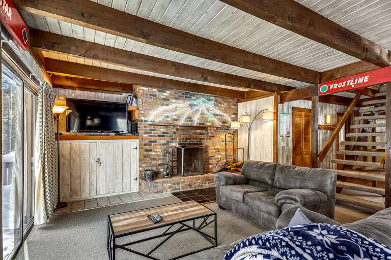 Rustic Room With Beams, Brick Fireplace, And Wooden Stairs In Vacation Rental