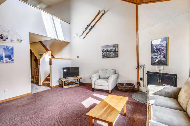 Vacation Rental Living Space With Light Sofas, Ski Decor, And Steep Stairs