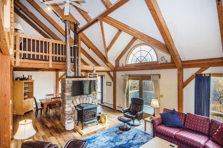 Vaulted Wooden Beams Frame A Spacious Interior With A Plush Seating Area And A Stony Hearth