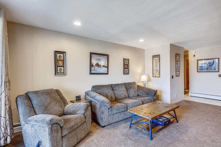 Living Space With Sofa Set And Coffee Table, Framed Pictures On Cream Walls, Subtle Lighting