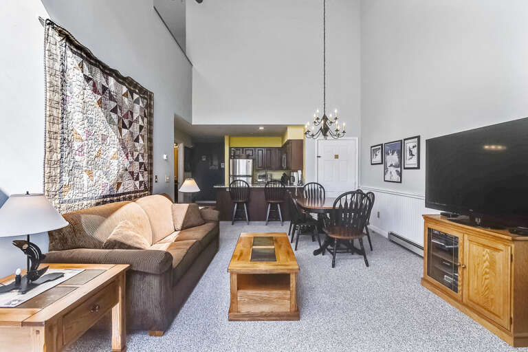 Living Room With Large Sofa, Wooden Furniture, And Quilt Wall Hanging