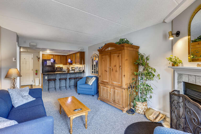 Living Space With Blue Sofas, Wooden Cabinet, Kitchen View And Fireplace