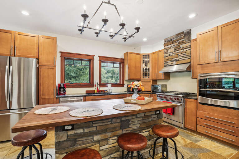 Spacious Kitchen With Stone Island, Stainless Steel Appliances, And Wooden Cabinets