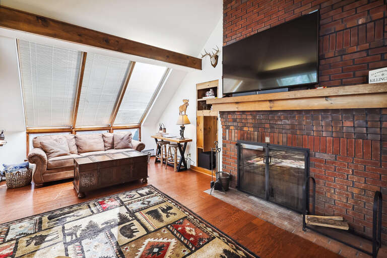 Vacation Rental Room With Vaulted Ceiling, Brick Fireplace, And Beam-supported Roof